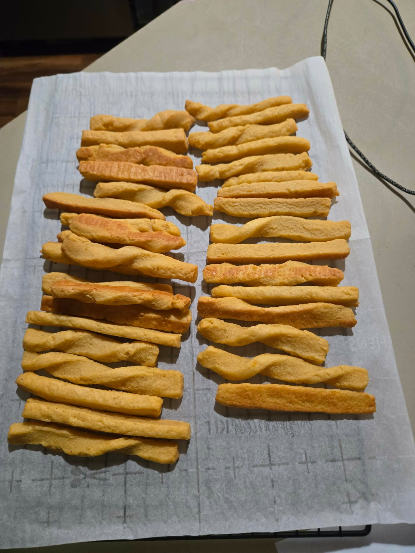 Rows of crisp golden butter twist cookies on parchment